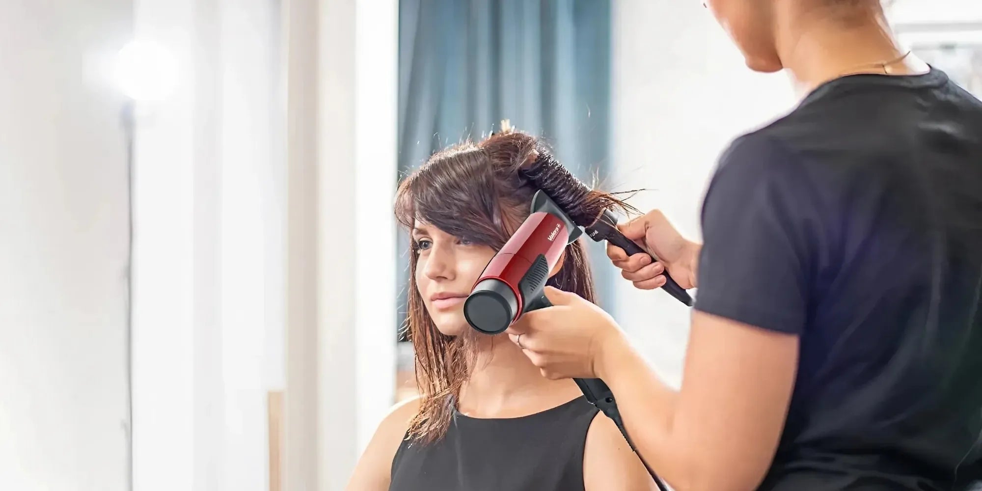 Kapper gebruikt rode Matrix AI haardroger om het haar van een jonge vrouw te stylen